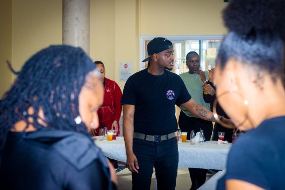 A group of people socialising, with a man in a black shirt engaging with others.
